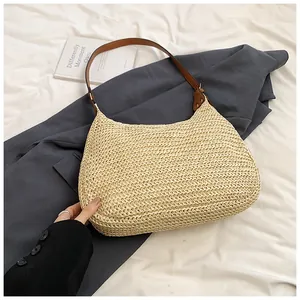 Detail of woven straw shoulder bag with brown leather strap on minimalist background