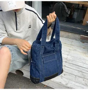 Close-up of a dark blue denim tote bag with reinforced black base and a front flap pocket