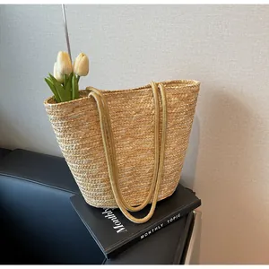 Detailed close-up of woven straw texture and dual rope handles on a large summer beach tote