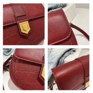 Detail of wine red leather saddle bag with crocodile texture and gold shield lock