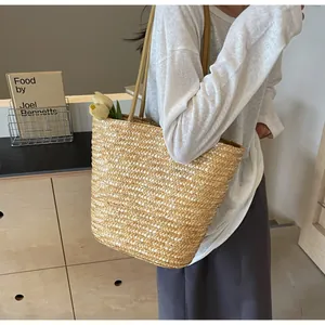 Close-up of woven straw tote bag featuring dense plain weave and matching twin straps
