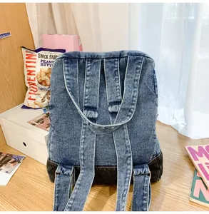 Detail shot of a blue and grey patchwork denim backpack on a desk with magazines