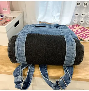 Detailed bottom view of a dual-tone denim backpack with silver adjustable buckles and stitching