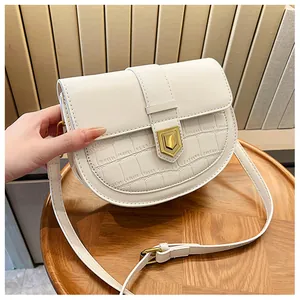 Detail of white saddle bag with crocodile texture and gold shield lock buckle