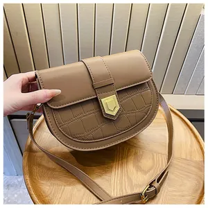 Close-up of brown saddle bag with crocodile texture and golden pentagon metal buckle