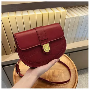 Detailed view of dark red saddle bag featuring crocodile texture and gold shield buckle
