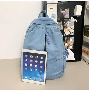 Detail van de gewassen denim rugzak met blauwe stoftextuur en zijvak en witte tablet