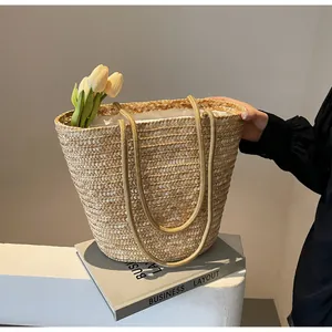 Detail of straw woven tote with dual handles, fabric lining and natural texture