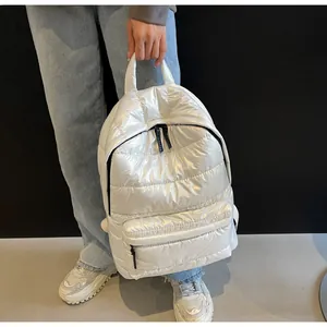 Close-up of bright white quilted puffer backpack featuring contrasting black zippers and handle