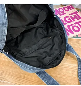 Interior detail of large denim backpack showing black lining and zip pocket storage