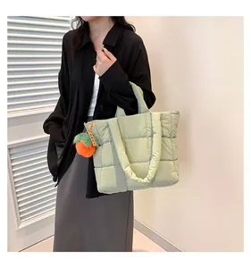 Macro view of light green quilted tote bag featuring a decorative orange persimmon plush charm