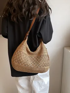 Bohemian hollow straw crossbody bag with brown leather strap worn by a model
