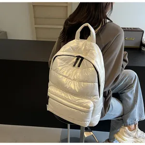 Detailed close-up of cream quilted puffer backpack showing the shiny fabric and zippers