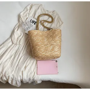 Detail of hand-woven straw tote bag on fabric with natural woven texture and long handles