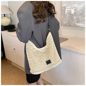 Detail of hand-woven hollow-out mesh shoulder bag with a black logo patch