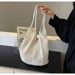 Close-up of a white hand-woven crochet tote bag with a hollow-out mesh texture design