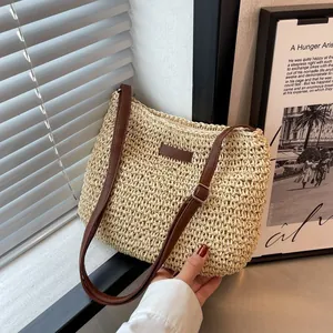 Dettaglio borsa a tracolla in paglia intrecciata beige con cinturino in pelle marrone e zip