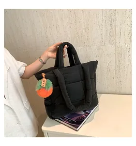Detail of black quilted puffer tote bag with plush charm and soft padded handles