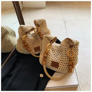 Close-up of beige crochet tote bag with wooden bead handle and leather logo patch detail