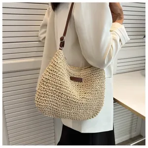 Dettaglio della borsa a tracolla in paglia beige con cinturino in pelle marrone e trama