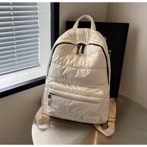 Detailed macro of white quilted puffer backpack featuring shiny fabric and metal zippers