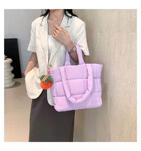 Close-up of a light purple quilted tote bag with orange puff pendant and nylon texture
