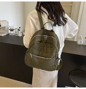 Zaino in nylon trapuntato verde militare visto di lato su una modella in un caffè