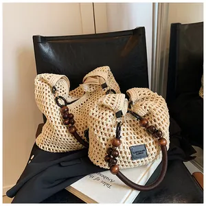 Detail of hollow woven tote bag featuring dark brown wooden bead handles and leather logo