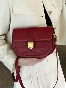 Vintage burgundy crocodile pattern saddle bag with gold buckle on a stylish model