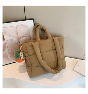 Close-up of quilted down tote bag in camel color with a cute plush charm and soft padding