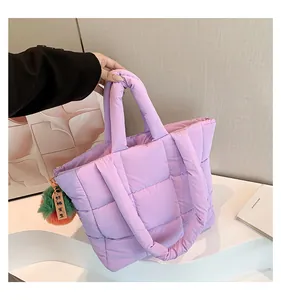 Detail of purple quilted down tote bag with plush charm and soft padded handles