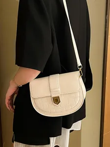 Cream white saddle bag with crocodile texture and gold hardware on black blazer outfit
