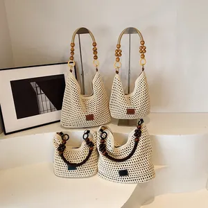 Close-up of beige woven tote bags featuring wooden bead handles in two sizes on a white stand