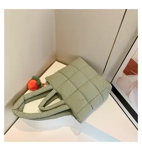 Detail of light green quilted down tote bag with a cute orange plush ball charm