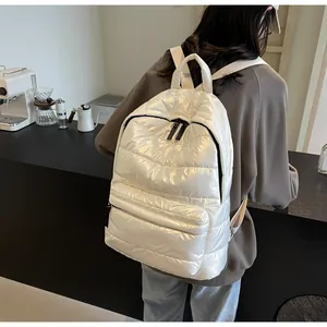 Detail of white quilted puffer backpack with glossy finish and durable black zippers