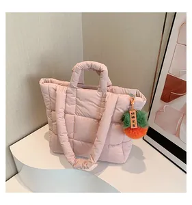 Detail of pink quilted tote bag with cute persimmon plush charm and themed decoration
