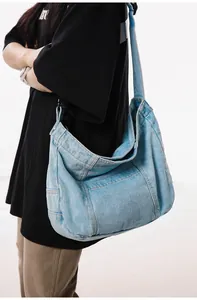 Light blue washed denim hobo bag shown on shoulder featuring wide strap and large capacity