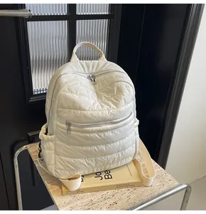 Dettaglio dello zaino trapuntato in nylon crema su tavolo in marmo e telaio in metallo