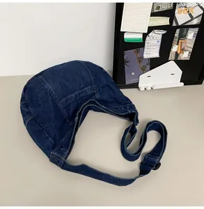 Detailed view of dark blue denim hobo bag with contrast stitching and adjustable strap