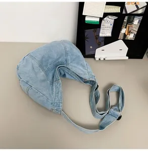 Close-up of light blue denim crossbody bag showing fabric texture and wide shoulder strap
