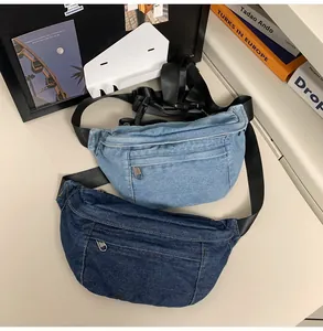 Detail view of denim waist bags in light and dark blue showing zippers and nylon straps
