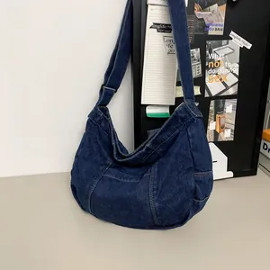 Detail of dark blue denim tote bag showing patchwork design and adjustable wide strap