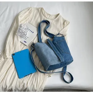Detail view of a patchwork denim bucket bag with pocket design on cream dress background
