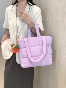 Quilted purple puffer tote bag with a cute persimmon plush charm shown by model