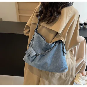 Detail view of denim hobo bag featuring decorative metal chain and mini pouch attachment