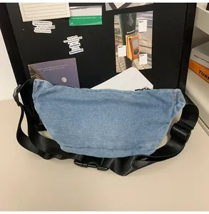 Detail of light blue denim crossbody waist bag with adjustable black strap and buckle