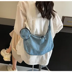 Dettaglio della borsa a mezzaluna in denim azzurro con portamonete rotondo abbinato sulla spalla