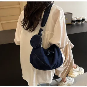 Dettaglio della borsa hobo in denim blu scuro con pochette rotonda sulla tracolla