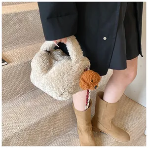 Detail der beige Teddy-Plüschtasche mit süßem braunem Pudel-Anhänger für den Winter
