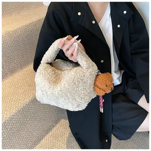 Detail der flauschigen cremefarbenen Beuteltasche mit süßem Teddybär-Anhänger